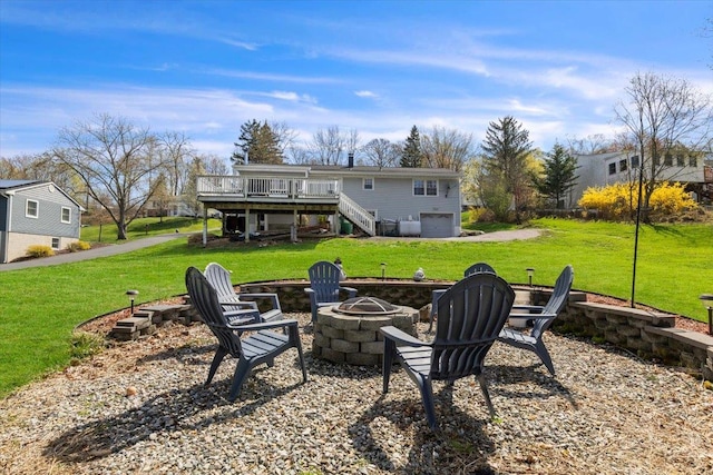 rear view of property featuring a fire pit, a lawn, a wooden deck, and stairs