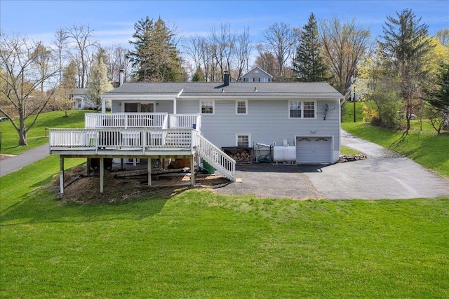 back of house featuring driveway, a wooden deck, an attached garage, stairs, and a yard