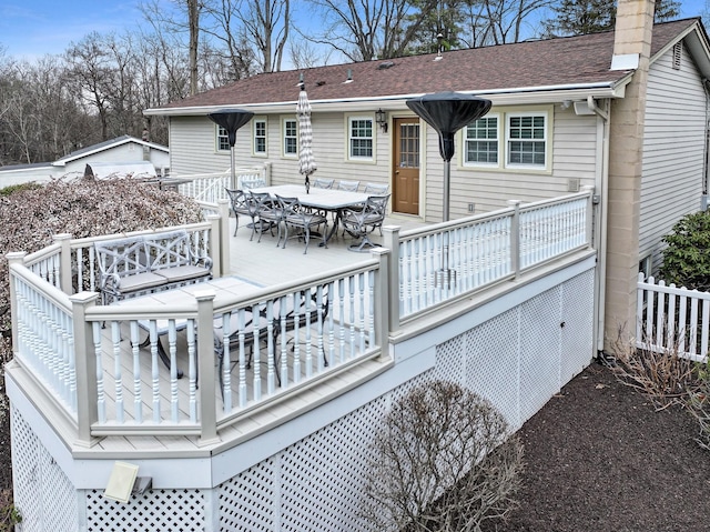back of property featuring a deck, a chimney, outdoor dining space, fence, and roof with shingles