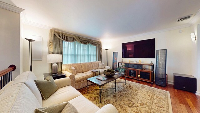 living room with visible vents, crown molding, and wood finished floors