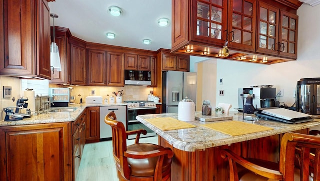 kitchen featuring a sink, a breakfast bar, light wood-style floors, and stainless steel appliances