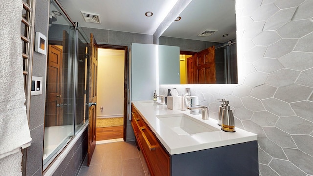 bathroom with tiled shower / bath, a sink, and visible vents