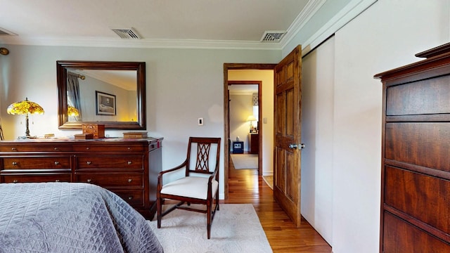 bedroom featuring crown molding, wood finished floors, baseboards, and visible vents