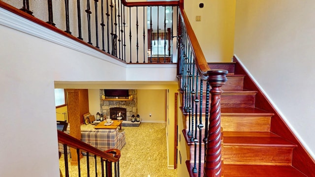 stairs featuring carpet floors, a towering ceiling, and a fireplace