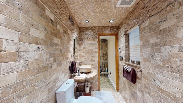 bathroom with toilet, a sink, and visible vents