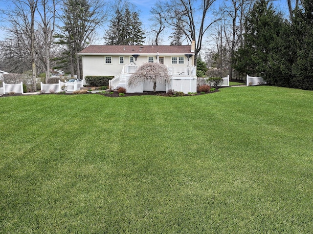 back of property featuring a chimney, fence, and a yard