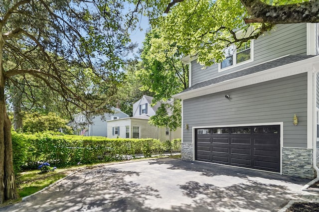 56 Drake Rd, Scarsdale, NY 10583 - view of side of home with a garage, stone siding, and asphalt driveway