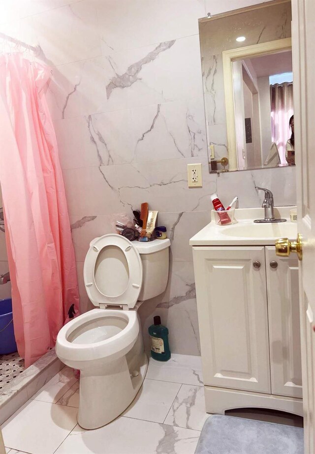 bathroom featuring marble finish floor, toilet, vanity, a shower with curtain, and tile walls