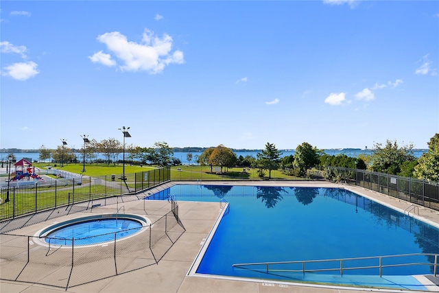 pool featuring a patio area, a lawn, playground community, fence, and a hot tub