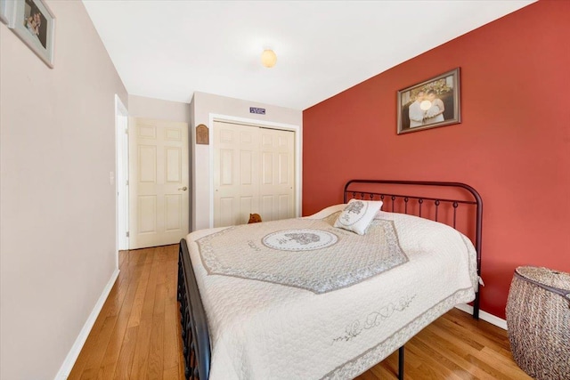 bedroom with baseboards, light wood finished floors, and a closet