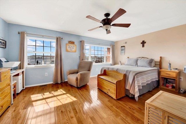 bedroom with baseboards, a ceiling fan, light wood-style floors, and visible vents