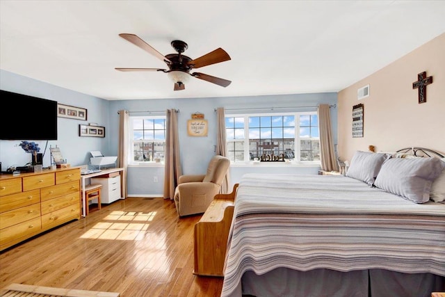 bedroom with light wood finished floors, baseboards, visible vents, and ceiling fan