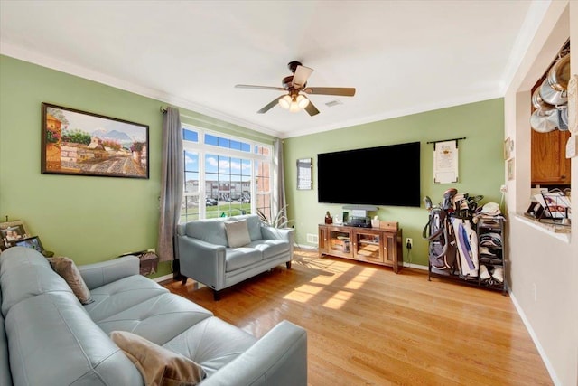 living room with light wood-style flooring, ornamental molding, baseboards, and ceiling fan