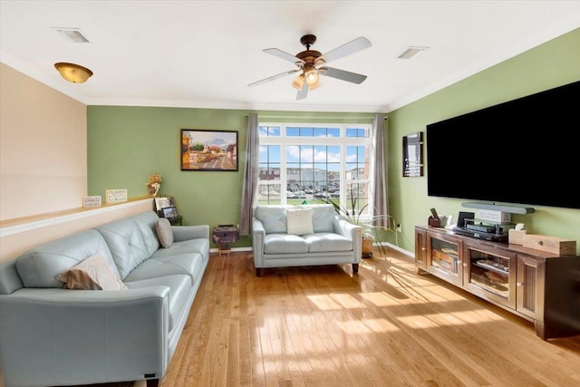 living room with crown molding, visible vents, light wood finished floors, and ceiling fan