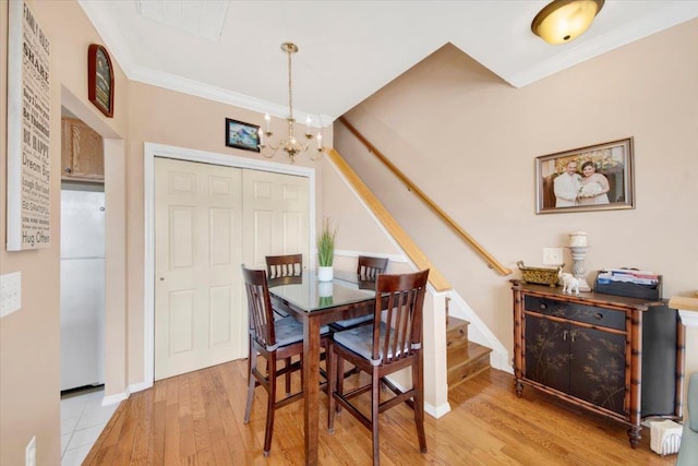 dining room with stairway, an inviting chandelier, ornamental molding, and light wood-style floors