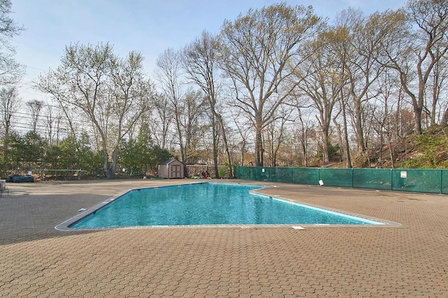 pool featuring an outdoor structure, a storage unit, a patio, and fence
