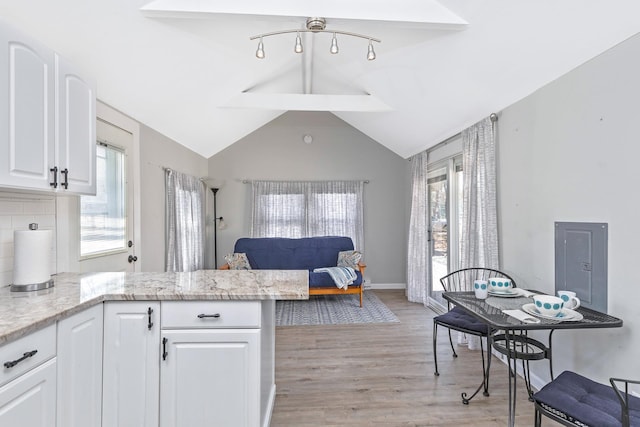 572A Montauk Hwy, Westhampton Beach, NY 11978 - kitchen with lofted ceiling, light wood finished floors, light stone countertops, a peninsula, and white cabinetry