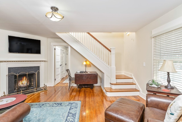 572A Montauk Hwy, Westhampton Beach, NY 11978 - living room featuring baseboards, a lit fireplace, stairs, and hardwood / wood-style floors