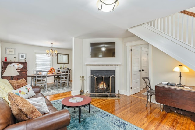 572A Montauk Hwy, Westhampton Beach, NY 11978 - living room with baseboards, a warm lit fireplace, a notable chandelier, and light wood-type flooring