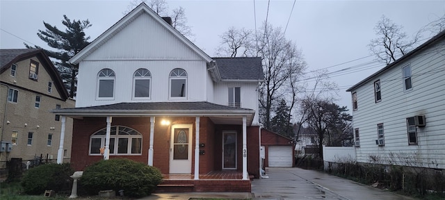 view of front of property featuring driveway, an outbuilding, a garage, a shingled roof, and covered porch