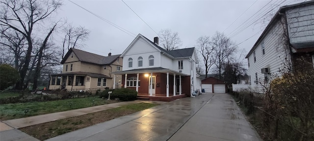 victorian house with an outbuilding, a porch, a chimney, a garage, and driveway