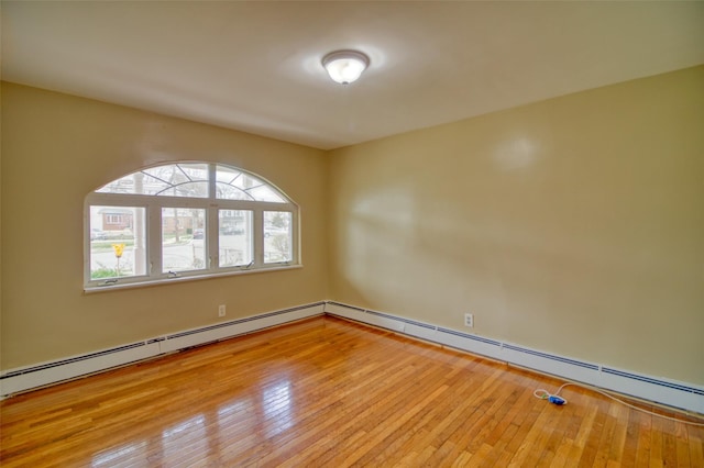 empty room with a baseboard heating unit and hardwood / wood-style flooring