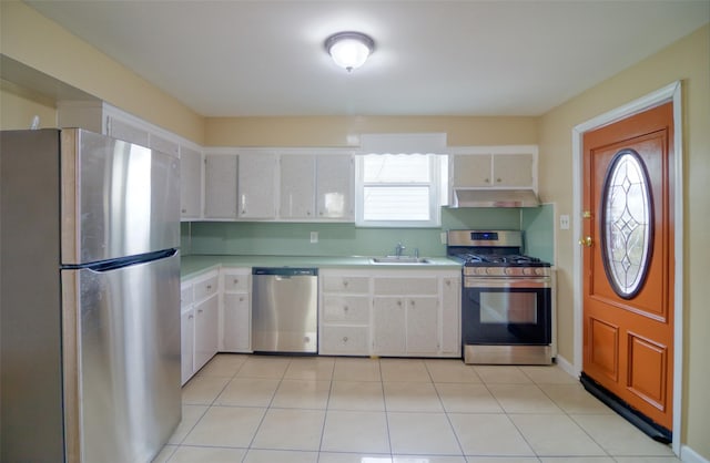 kitchen with a sink, light countertops, appliances with stainless steel finishes, under cabinet range hood, and white cabinetry