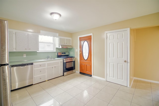 kitchen featuring light countertops, light tile patterned flooring, white cabinets, appliances with stainless steel finishes, and a sink