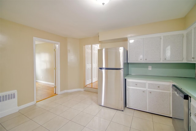 kitchen featuring light tile patterned floors, baseboards, light countertops, appliances with stainless steel finishes, and radiator heating unit