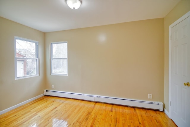 empty room with wood finished floors, a baseboard heating unit, and baseboards