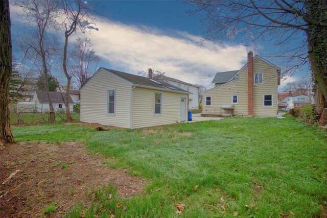 rear view of property featuring a yard, fence, and a chimney