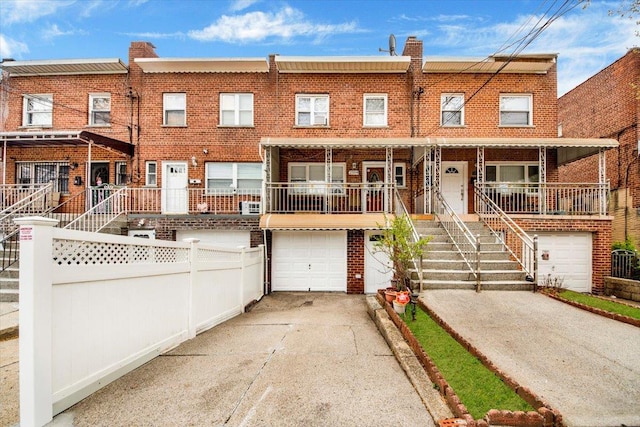 2559 Seymour Ave, Bronx, NY 10469 - townhome / multi-family property featuring brick siding, an attached garage, stairs, and concrete driveway