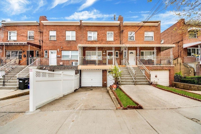 2559 Seymour Ave, Bronx, NY 10469 - townhome / multi-family property with stairway, concrete driveway, an attached garage, a porch, and brick siding