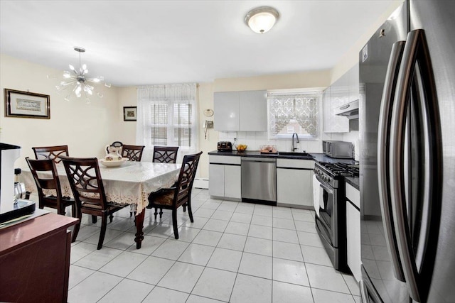 2559 Seymour Ave, Bronx, NY 10469 - kitchen with dark countertops, a sink, a chandelier, appliances with stainless steel finishes, and under cabinet range hood