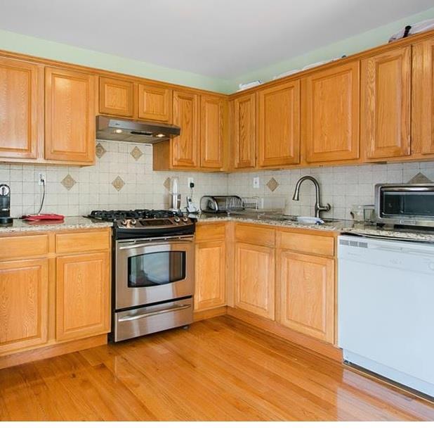 1933 Colden Ave, Bronx, NY 10462 - kitchen featuring under cabinet range hood, light wood-type flooring, backsplash, and appliances with stainless steel finishes