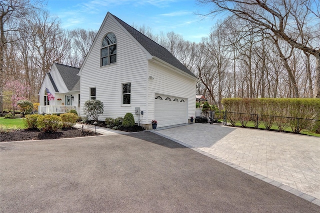 view of side of home featuring a shingled roof, aphalt driveway, and fence