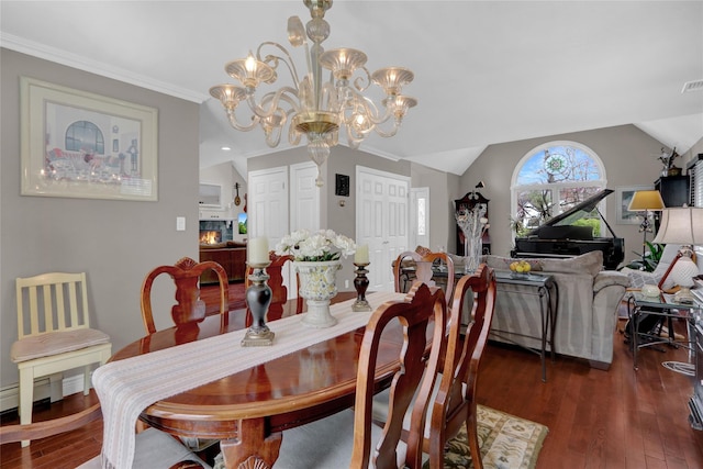 dining room with lofted ceiling, a chandelier, wood finished floors, and visible vents
