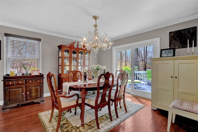 dining space with a chandelier, wood finished floors, visible vents, and crown molding