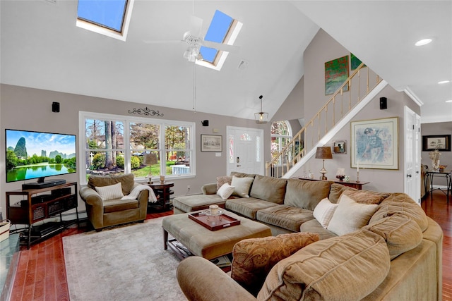 living room with stairway, high vaulted ceiling, wood finished floors, a skylight, and recessed lighting