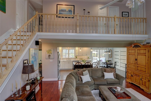 living area featuring baseboards, wood finished floors, a towering ceiling, and stairs