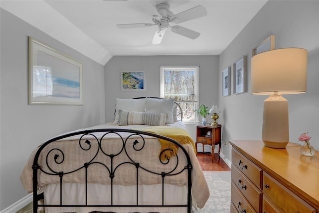 bedroom with a baseboard heating unit, lofted ceiling, light wood-style floors, and baseboards
