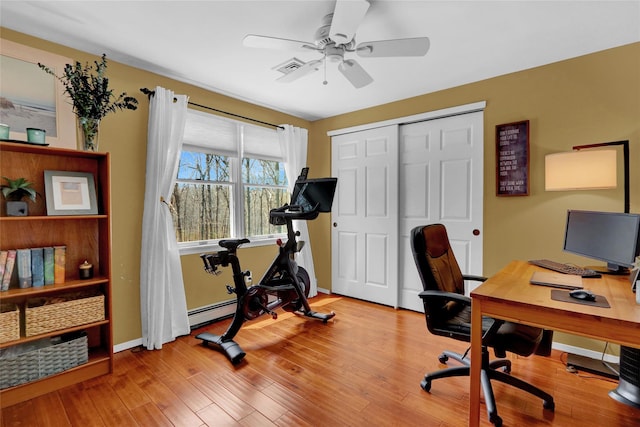 office featuring a baseboard heating unit, baseboards, a ceiling fan, and wood finished floors