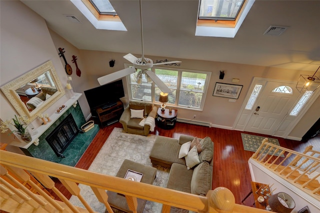 living area with a baseboard heating unit, a high end fireplace, lofted ceiling with skylight, and visible vents