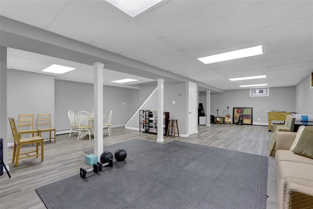 interior space featuring baseboards, a paneled ceiling, and wood finished floors