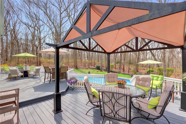 wooden deck with a gazebo, outdoor dining space, and an outdoor pool