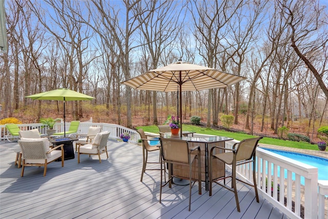 wooden deck with outdoor dining area, an outdoor pool, a fire pit, and a fenced backyard