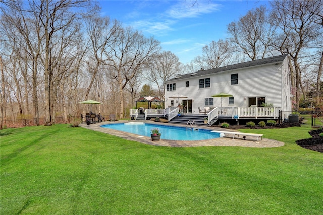 view of swimming pool with a yard, a diving board, a deck, and a fenced in pool