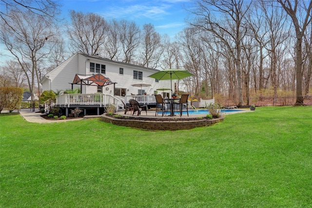 back of property featuring a wooden deck, a yard, an outdoor pool, and fence