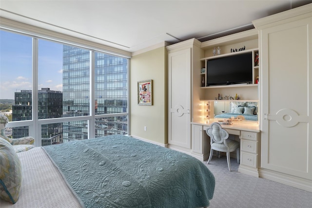 carpeted bedroom featuring built in desk, floor to ceiling windows, and ornamental molding