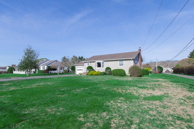 view of front of property with a garage, driveway, a chimney, and a front lawn